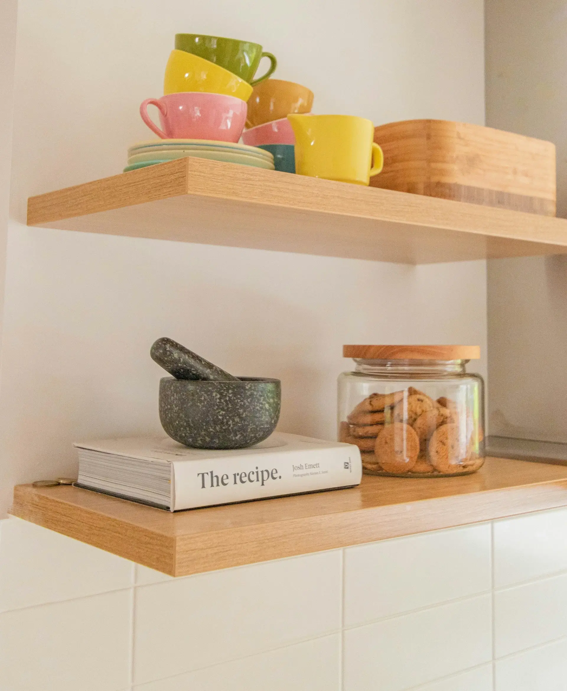 Graphic of a recipe book on a shelf with a jar of cookies, and mugs and plates.